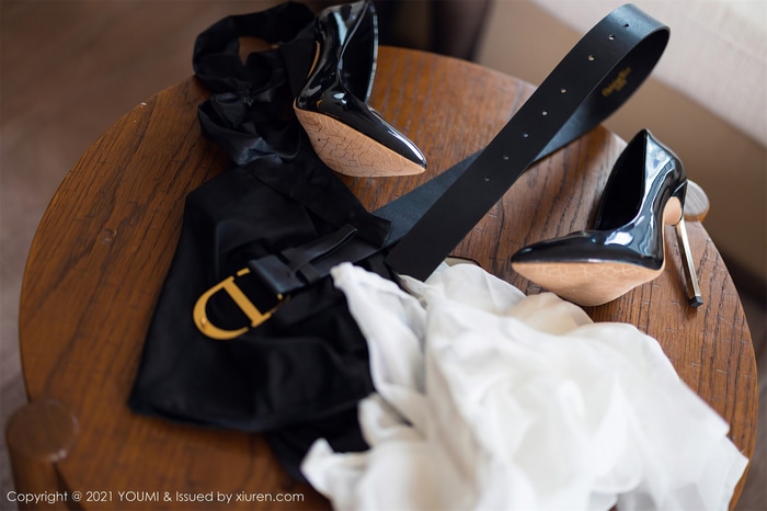 Black patent leather heels and Dior belt on a wooden table