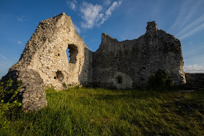 Stone ruins of a castle on a grassy hill under a blue sky