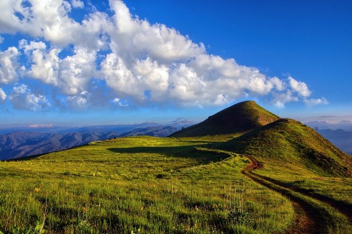 Green rolling hills under a blue sky with clouds