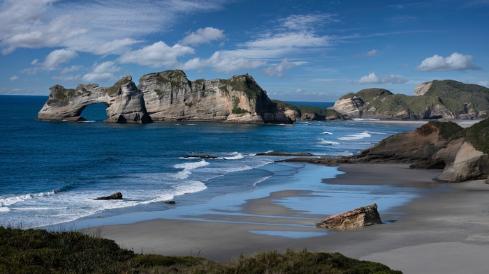 Wharariki Beach rock formation and sea under blue sky