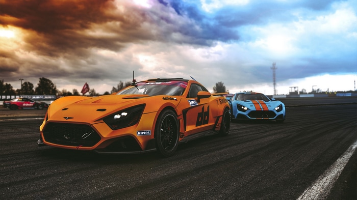 Two race cars on a track under a cloudy sky