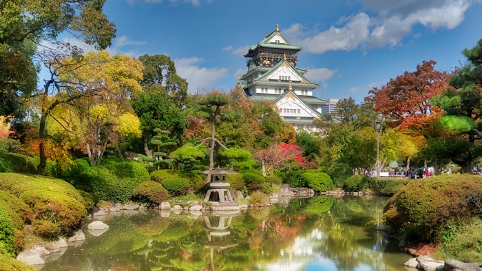 Osaka Castle garden with autumn trees and reflection