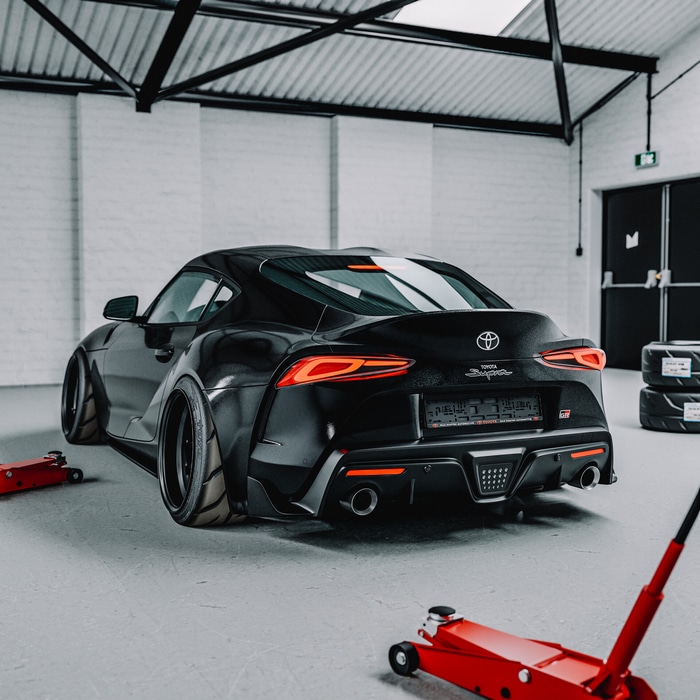 Black Toyota Supra in a garage with car jacks