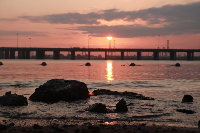 Sunset over the sea with a bridge and rocks