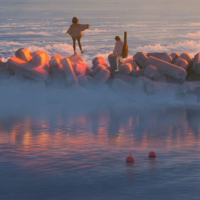 Two women with a guitar by the sea at sunset