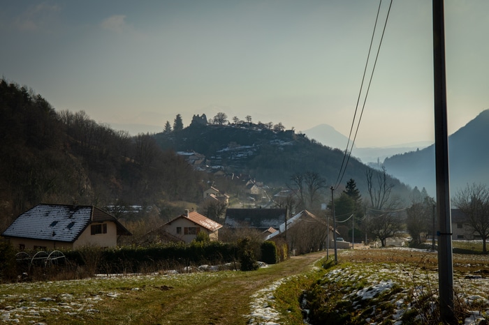 Winter village with snow-covered houses and a castle ruin on a hill