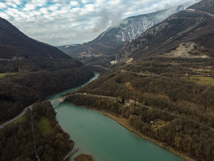 River flowing through a valley with mountains and a bridge in France