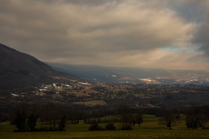 A cloudy sky over a valley with mountains and a village