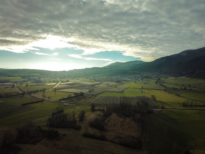 Aerial view of agricultural fields and mountains under cloudy sky
