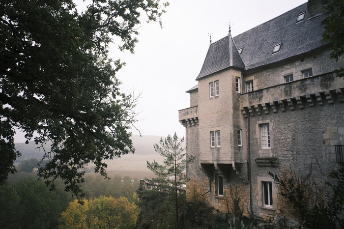 Stone mansion with a turret and trees