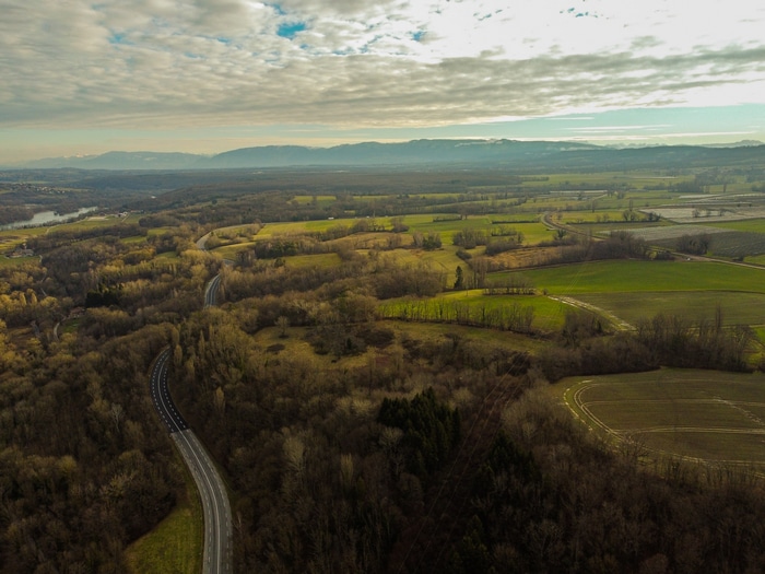 Aerial view of a winding road through a forest and fields