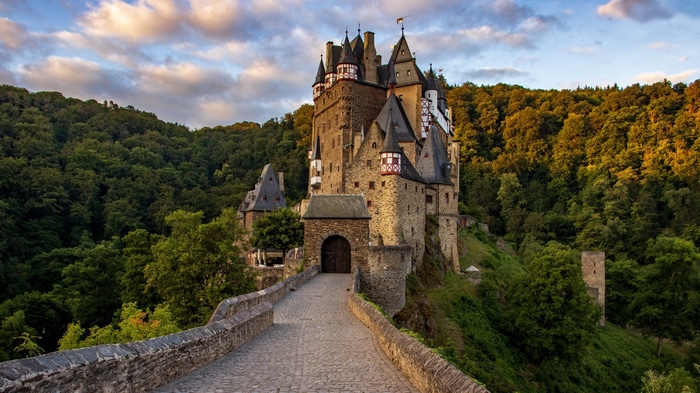 4K Eltz Castle surrounded by green trees and clouds