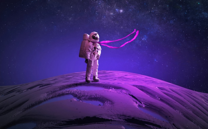 Astronaut standing on a purple planet with stars in the background