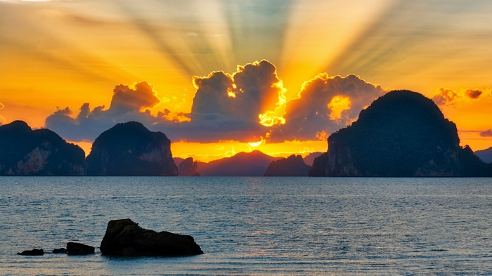 Sunset over islands with sun rays and rocks
