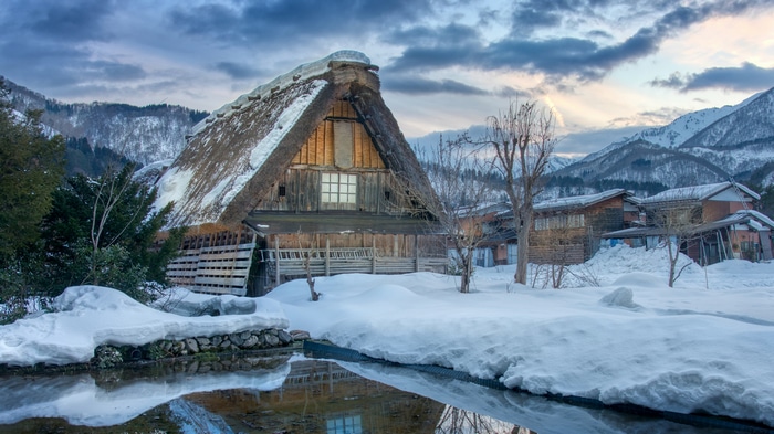 4K snow-covered village with mountains and reflection