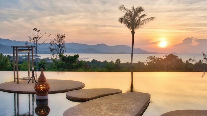 4K sunset over mountains with palm trees and infinity pool