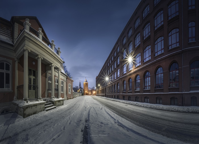 Winter evening street with buildings and tower in Poland