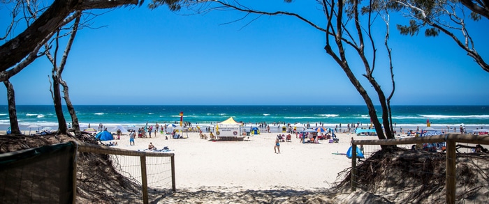 People enjoying a sunny day at the beach with the ocean waves.
