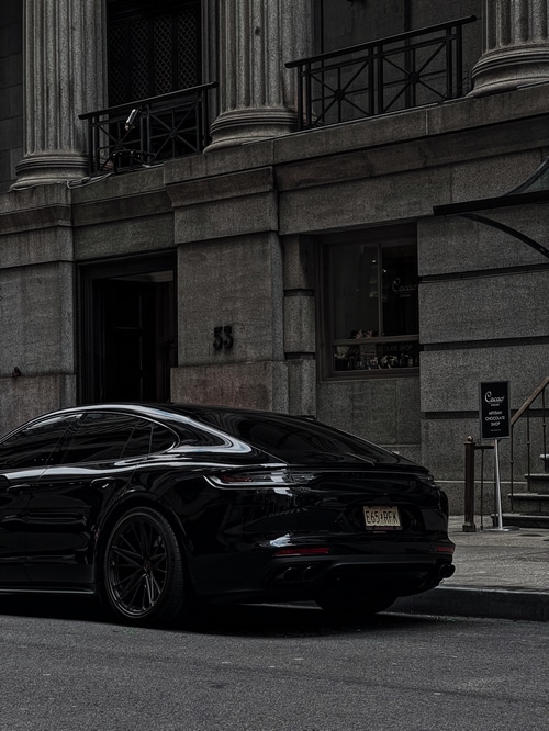 Black Porsche Panamera parked in front of a stone building