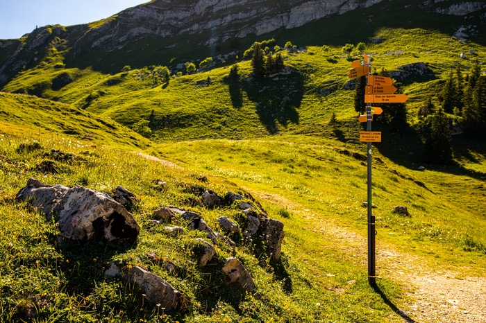 Hiking signpost in the Swiss Alps with green hills
