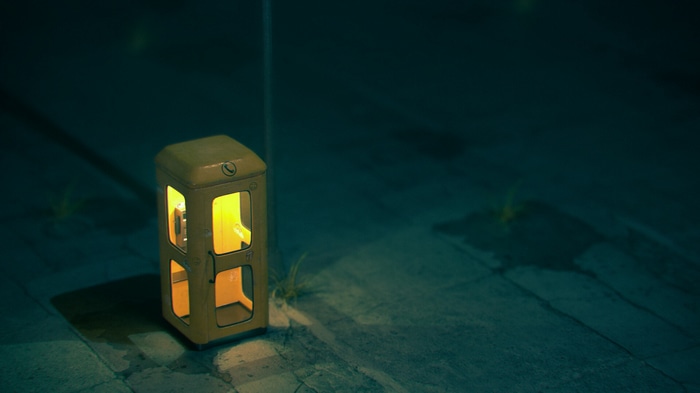 A yellow phone box at night