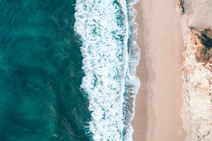 Aerial view of ocean waves crashing on a sandy beach