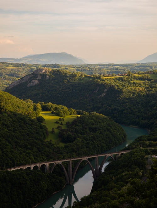 Arched railway bridge over a river in a green gorge