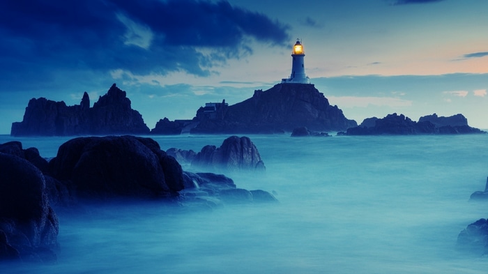 4K Lighthouse on Rocky Island in Blue Water