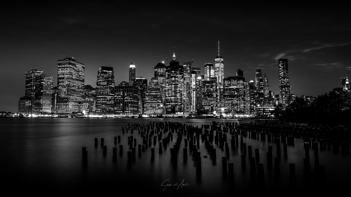 New York City skyline at night with water and pilings
