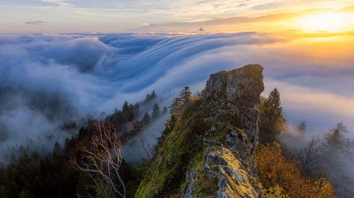 4K sunset over a sea of clouds from a rocky peak