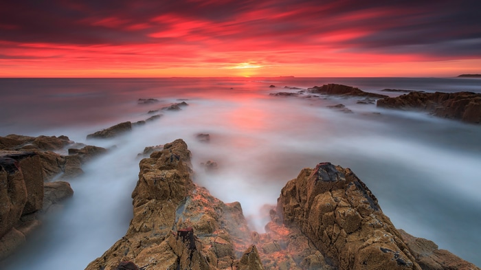 4K rocks and sunset glow over the ocean