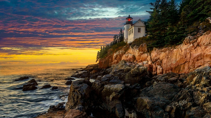 4K lighthouse on rocky coast at sunset