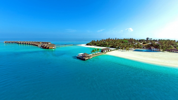 Overwater bungalows and tropical island resort in clear blue water