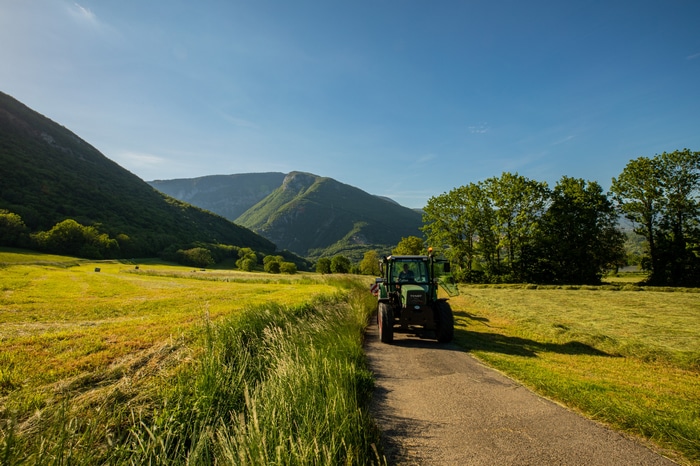 Tractor on a road in a mountain valley farm field