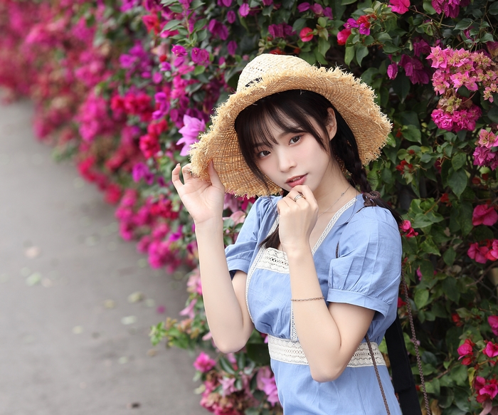 Woman with black hair wearing a straw hat and blue dress