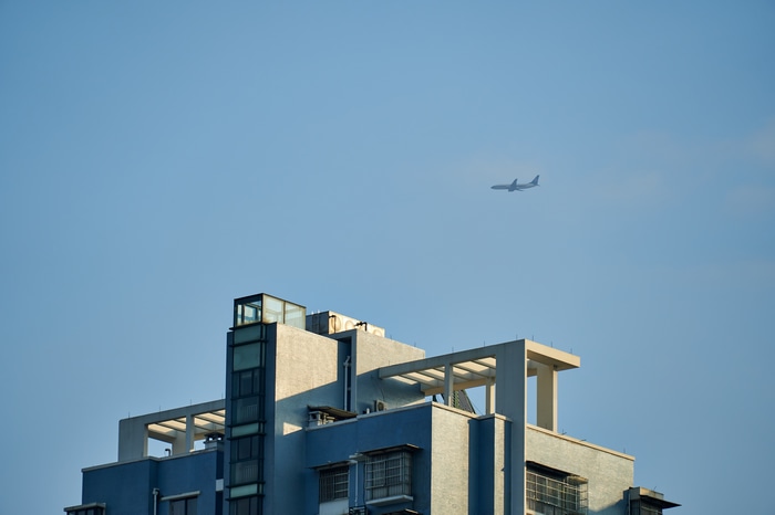 Airplane flying over modern building rooftops