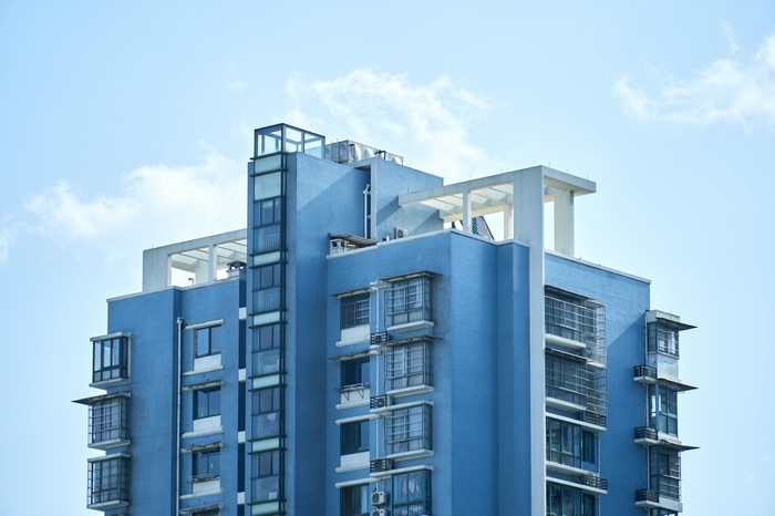 Blue apartment building against a cloudy sky