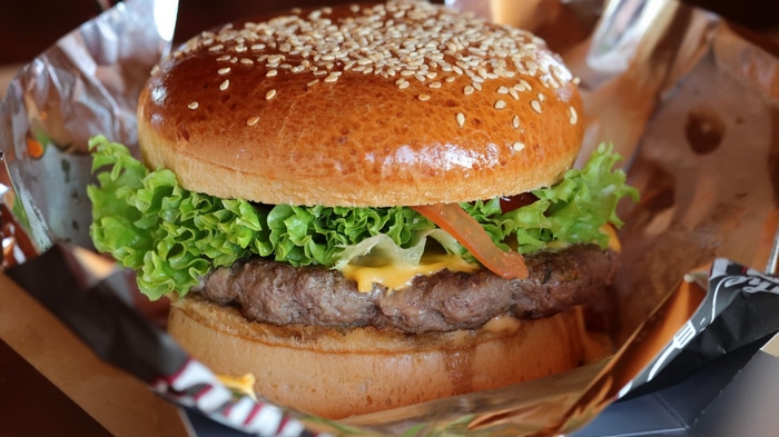 A close-up of a gourmet burger with sesame seed bun