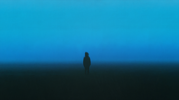 A lone figure stands in a dark, foggy landscape under a blue sky.