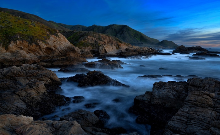 Rocky coastline with waves crashing at dusk