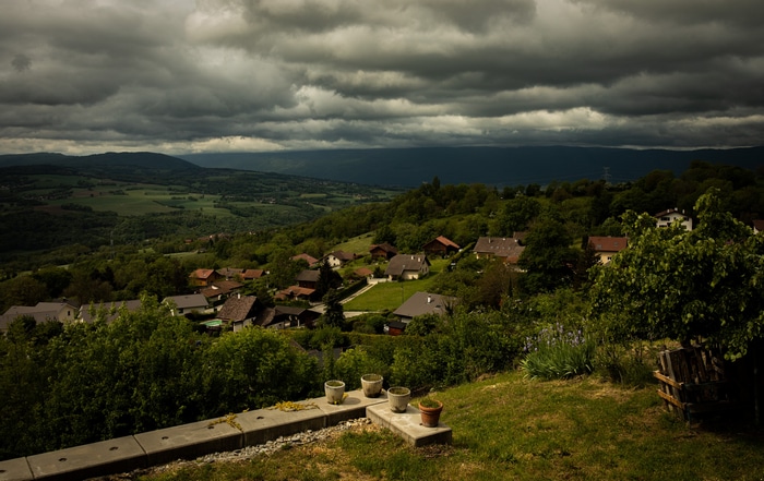 Village nestled in rolling hills under stormy clouds