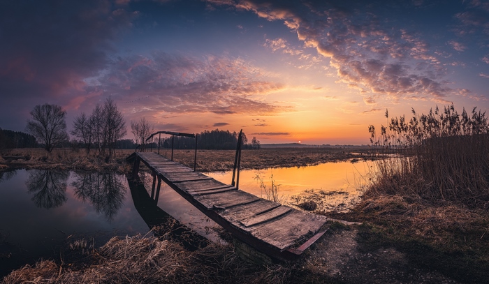 Wooden bridge over water at sunset