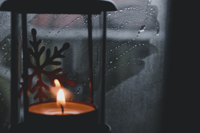 Candle lantern with snowflake on a rainy window