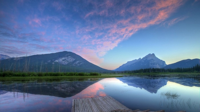 Sunset over mountains reflected in a lake with a wooden dock