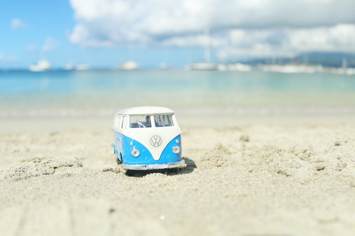 Blue and white Volkswagen van toy on a sandy beach