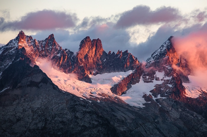Snowy mountains at sunset with pink clouds