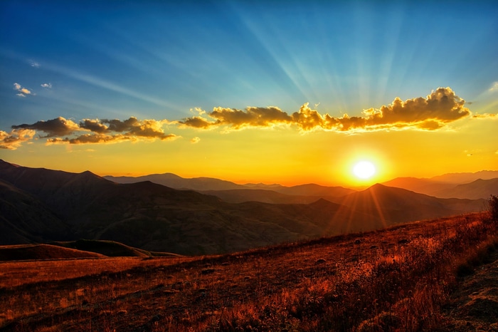Sunset over rolling mountains with sun rays