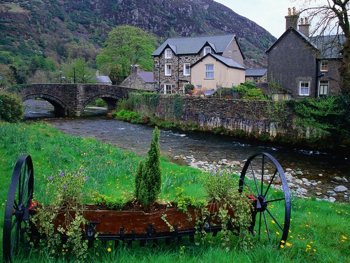 Stone bridge over a river with houses and mountains