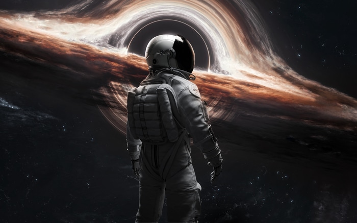 Astronaut facing a black hole and galaxy