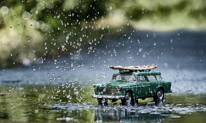 Green toy car with surfboard in the rain